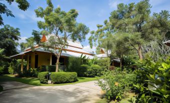 a house surrounded by a lush green garden , with trees and bushes surrounding the property at Poonyamantra Resort