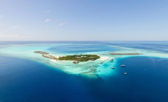 a beautiful aerial view of an island surrounded by clear blue water , with boats visible in the distance at Constance Moofushi