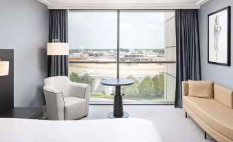 a hotel room with a bed , a chair , and a window overlooking a city view at Sofitel London Gatwick