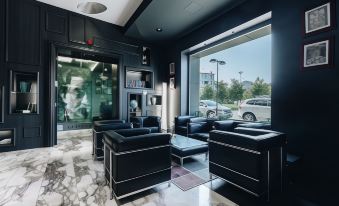 a luxurious black room with two black leather couches and a large window , allowing natural light to fill the space at Hotel Continental