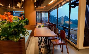 a modern dining room with a wooden table and chairs , surrounded by large windows overlooking the outdoors at Hotel Cianjur Cipanas