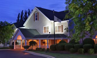 a large , two - story house with a wrap - around porch and a porch area lit up at night at Country Inn & Suites by Radisson, Ft. Atkinson, WI