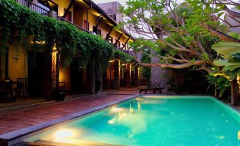 a courtyard with a pool surrounded by trees and bushes , creating a serene and inviting atmosphere at Rumah Batu Boutique Hotel