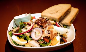 a large white bowl filled with a delicious salad , accompanied by two pieces of bread at Byrkjedalstunet Hotell