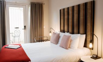 a large bed with white sheets and red pillows is in a room with a striped wall at Alexandra Place