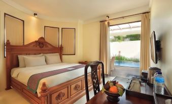 a bedroom with a large bed , wooden furniture , and a view of a swimming pool through the window at Aston Sunset Beach Resort - Gili Trawangan