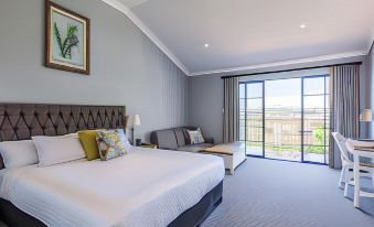 a modern hotel room with a large bed , couch , and sliding glass door leading to a balcony at Camden Valley Inn