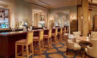 a modern bar with wooden tables and chairs , blue carpeting , and a well - appointed seating area at Country Inn & Suites by Radisson, Baltimore North/White Marsh