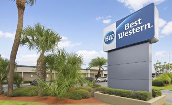 a tall palm tree stands in front of a blue sign for the best western hotel at Best Western Downtown Stuart