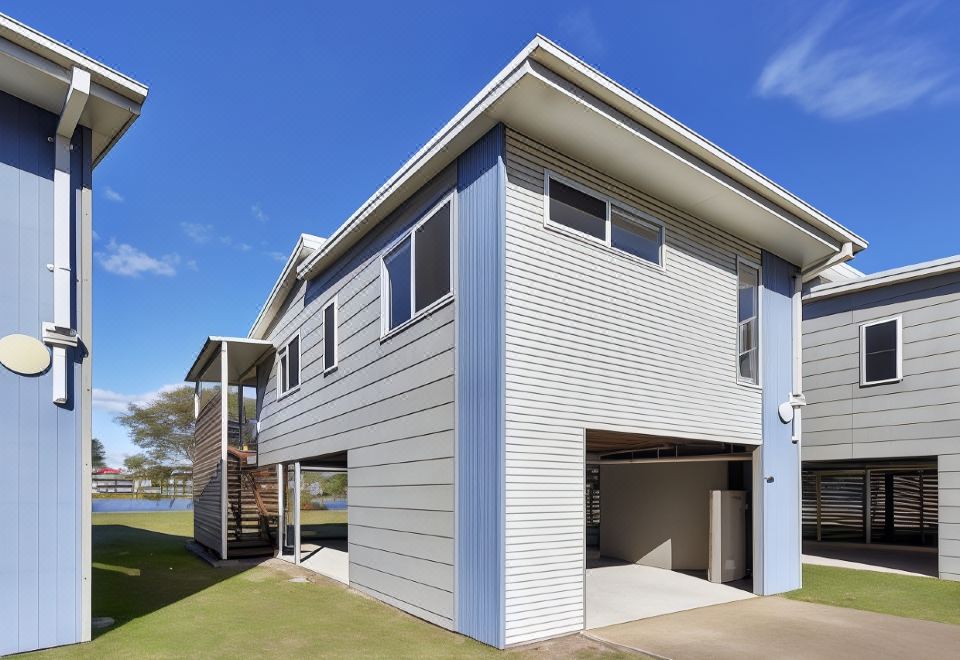 a blue and white two - story house with a garage attached to it , situated next to a body of water at Nrma Sydney Lakeside Holiday Park