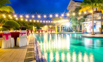 a large swimming pool with a white building in the background and string lights hanging from it at Novilla Boutique Resort