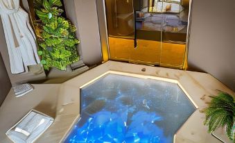 a modern bathroom with a large bathtub filled with blue water , surrounded by gold accents and plants at Dogana Resort