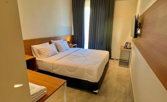 a hotel room with a double bed , a tv , and a window overlooking the city at The Royal Joglo