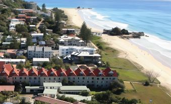 an aerial view of a coastal city with buildings , trees , and the ocean in the background at Sanctuary Beach Resort