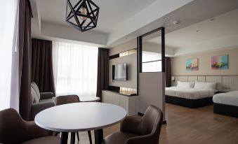 a modern hotel room with a round table and chairs , a television on the wall , and a bed in the background at Higher Hotel