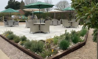 an outdoor dining area with several tables and chairs , surrounded by greenery and a water feature at The Red Lion Inn