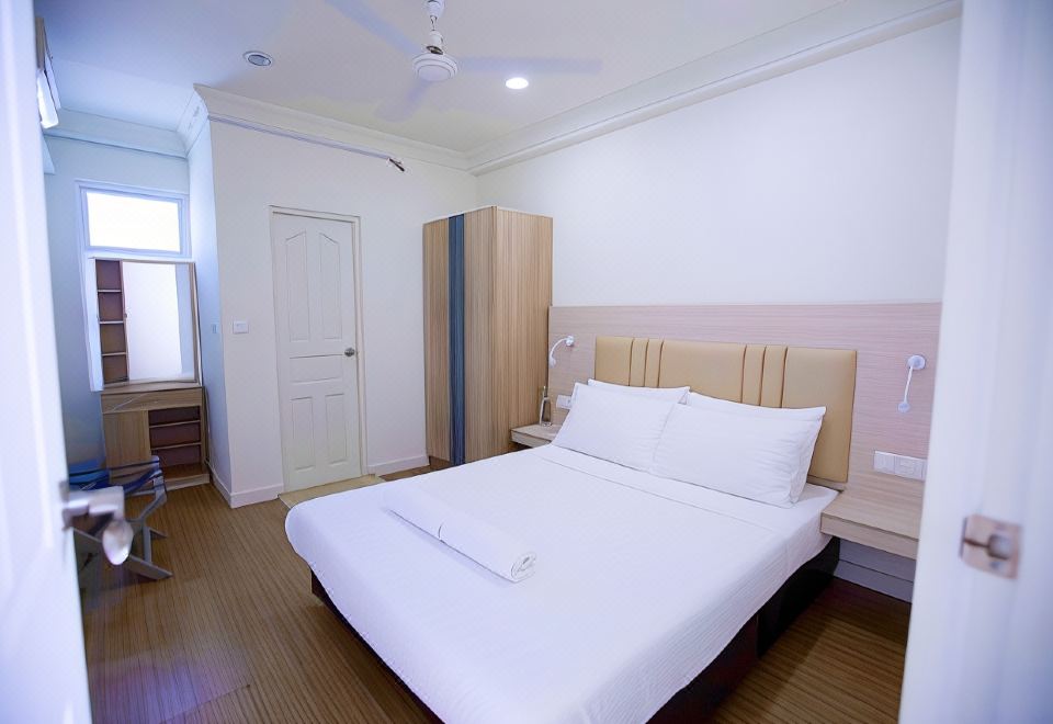 a hotel room with a white bed , wooden floors , and a closet , along with other furniture at Keyla Inn