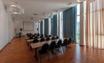 a large conference room with wooden floors , multiple rows of tables and chairs , and a large screen at the front at Sunscape Puerto Plata All Inclusive