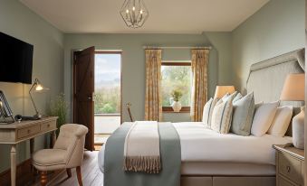 a large bed with white and blue linens is in a room with wooden floors , green walls , and a window at The Newbridge on Usk