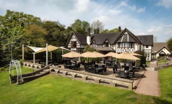 a large outdoor dining area with numerous tables and chairs , surrounded by a lush green lawn at The Bentley Brook Inn