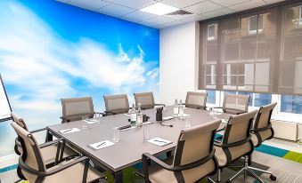 a conference room with a large table surrounded by chairs and water bottles , set against a backdrop of a blue sky at Villiers Hotel