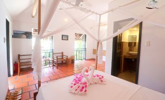 a bed with a white canopy and pink floral pillows is in a room with red flooring at Whale Island Resort