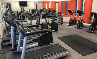 a gym with multiple exercise machines and a person on a treadmill in the middle at Woodland Grange