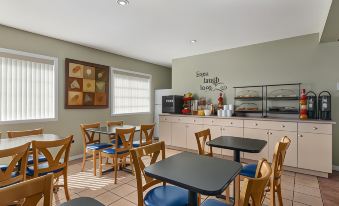 a dining area with several tables and chairs , along with a counter with various items on it at Grand Forks Inn