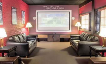 a cozy movie theater with comfortable seating , a large screen projector , and two leather couches at SureStay Plus Hotel by Best Western Lehigh Valley