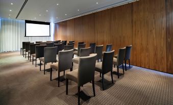 a conference room with rows of chairs arranged in a semicircle , and a projector on the wall at Cliff House Hotel