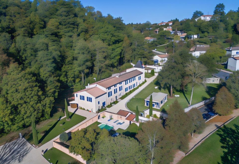 an aerial view of a large mansion surrounded by trees , with a pool visible in the foreground at Hotel Saint-Martin - Younan Collection