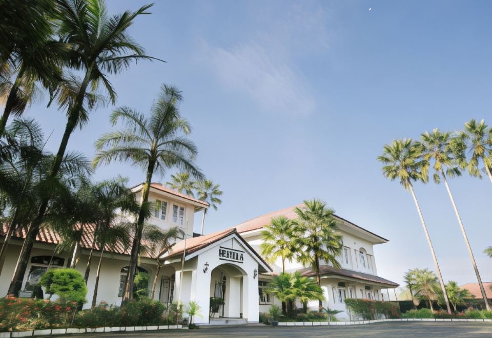 a white house with palm trees in front of it , under a clear blue sky at Sevilla Resort Magelang