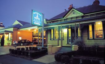 "a building with a blue sign that says "" william 's hotel "" is surrounded by bushes and has a car parked in front" at Alexandra Place