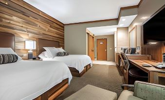 a modern hotel room with two beds , wooden walls , and a desk area , as well as a desk and chairs at Norfolk Lodge & Suites, Ascend Hotel Collection
