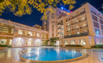 a large outdoor swimming pool surrounded by a hotel , with the surrounding buildings visible in the background at Palace Hotel