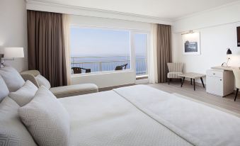 a luxurious hotel room with a large window offering a view of the ocean , white walls , and comfortable furniture at Bordoy Continental Valldemossa