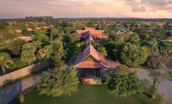 a bird 's eye view of a large , open - air building with red roofs surrounded by trees and greenery at Mane Hariharalaya