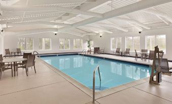 an indoor swimming pool surrounded by white walls , with several lounge chairs placed around it at Country Inn & Suites by Radisson, Fredericksburg, VA