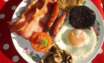 a plate filled with a variety of breakfast items , including eggs , bacon , sausage , mushrooms , and an egg on top of a croissant at Yew Tree Farm Cottages Congleton