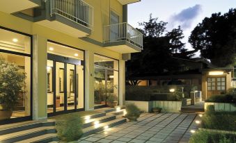 a modern , two - story building with balconies and greenery , illuminated by warm lights at night , situated on a sunny day at American Hotel