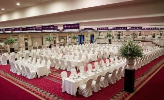 a large banquet hall with multiple tables covered in white tablecloths and chairs arranged for a formal event at Islamabad Marriott Hotel