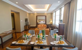 a dining table is set with plates , wine glasses , and napkins in a living room area at The Sunan Hotel Solo