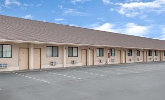 a row of buildings with a tan roof and beige walls are lined up in a parking lot at Knights Inn Pine Brook