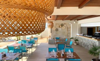 a modern restaurant with a unique wooden ceiling design , blue chairs and tables , and multiple tables set for dining at Hotel Savoy