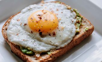 a slice of bread topped with an egg and pesto , sitting on a white plate at The Upper House Hotel