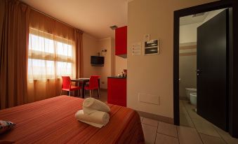 a modern hotel room with a bed , kitchenette , and bathroom , along with red curtains and white walls at Easy Space