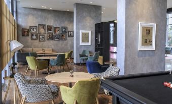 a modern office space with various pieces of furniture , including a pool table , chairs , and couches at Aloft New Delhi Aerocity
