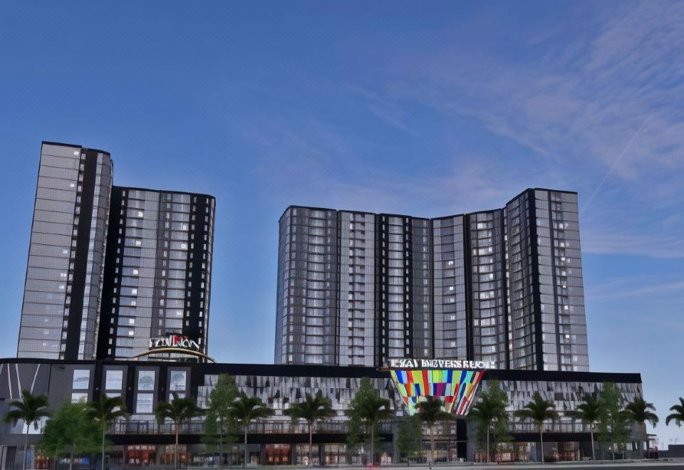 a tall , modern building with a colorful sign on top is shown against a blue sky at Hotel Horison Grand Serpong