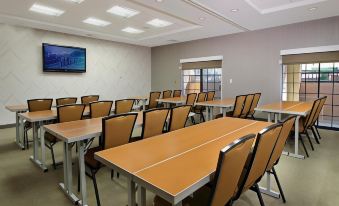 a conference room with wooden tables and chairs , a television on the wall , and a window at SpringHill Suites Madera