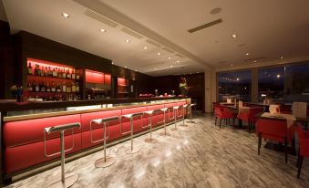 a modern restaurant with a long red bar and several chairs surrounding it , creating a cozy atmosphere at Antony Palace Hotel - Venice Airport